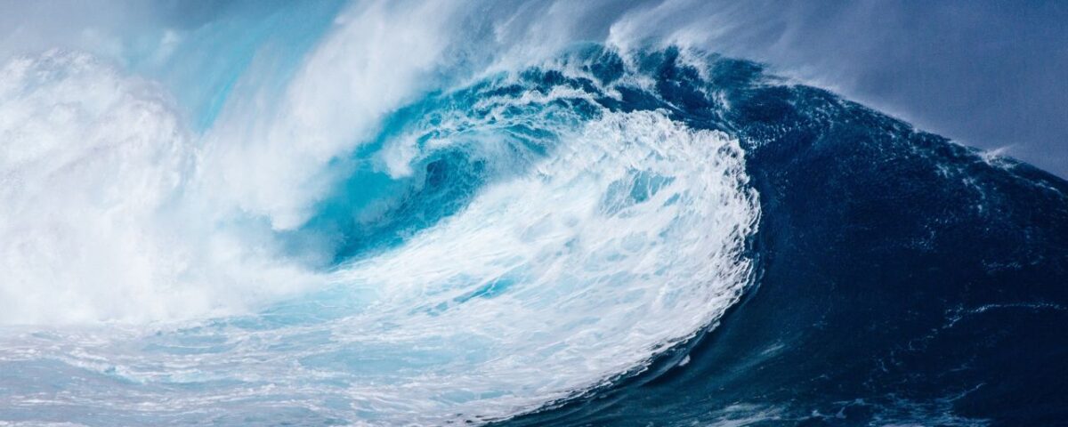 A large blue wave crashing into the ocean.