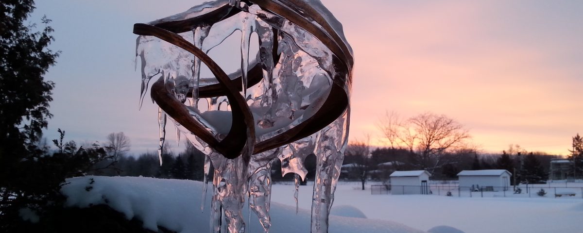 Icicles hanging from a wind spinner during winter at sunrise.