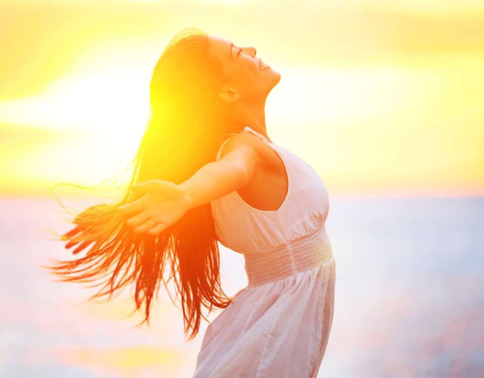 A woman with her arms outstretched at sunset.