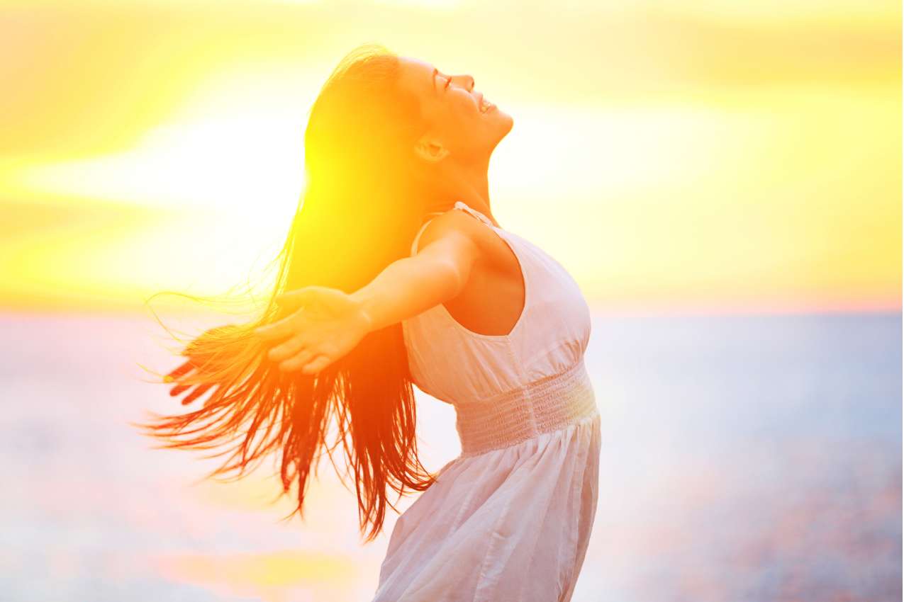 A woman with her arms outstretched at sunset.