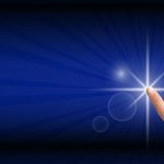 A hand pressing a button that looks like a bright white star against a vibrant blue background