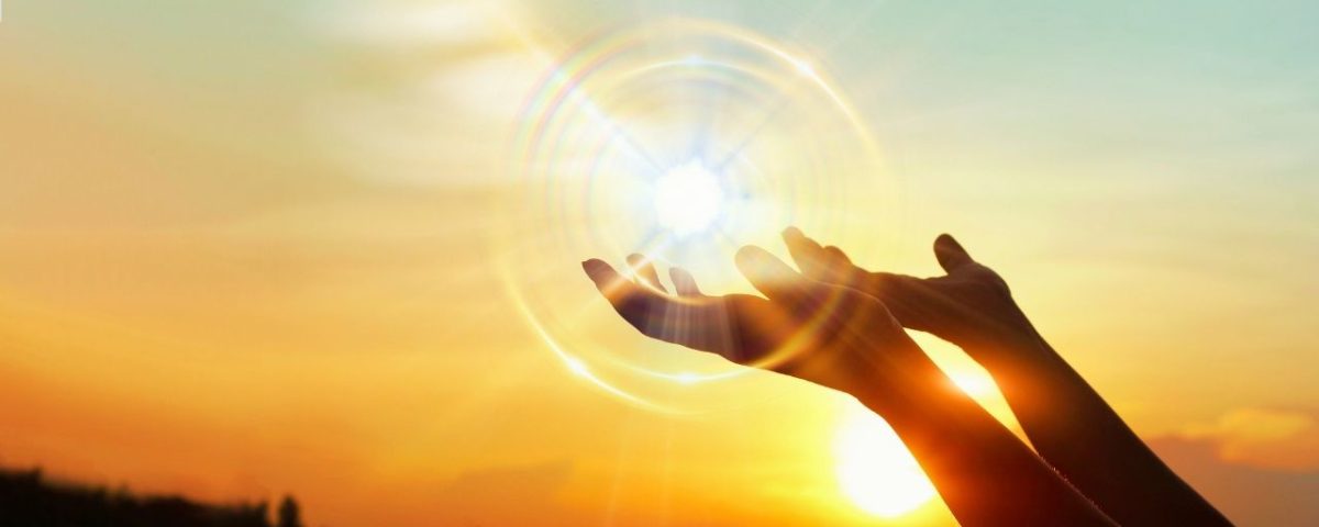 Hands uplifted towards a luminous sun orb, conveying themes of enlightenment and inspiration in a warm atmosphere.