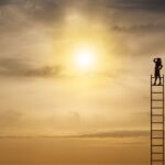 An individual on a ladder looks up at the sun, representing a pursuit of enlightenment and higher aspirations.